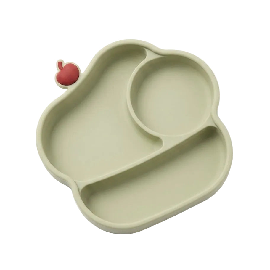 An organic-shaped silicone baby feeding tray in sage green, featuring three compartments and a small red apple-shaped silicone pick-up piece on the left side, shown on a clean white background.