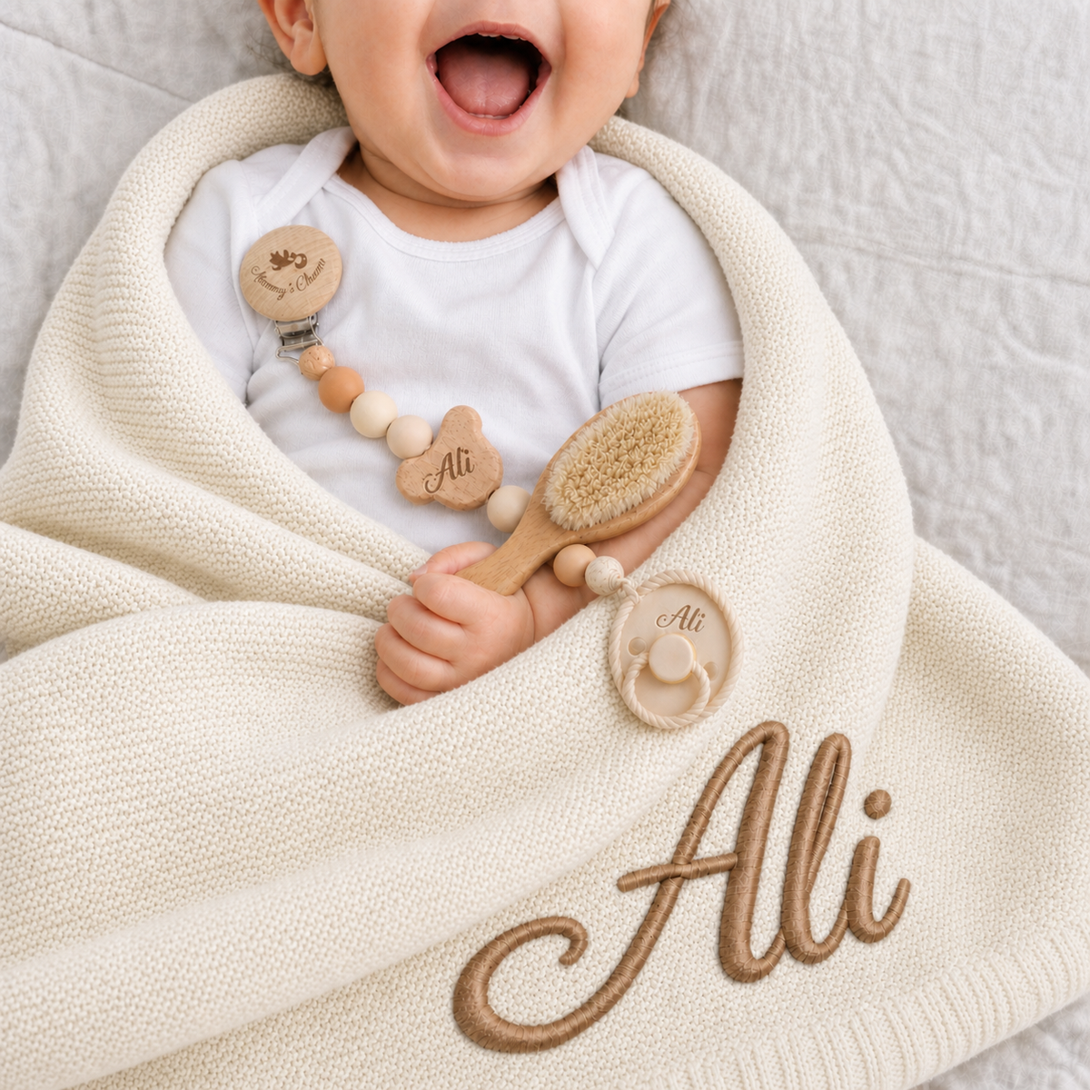 Baby Ali with a personalised knitted blanket, pacifier clip, brush and pacifier