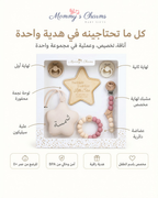 A baby gift set from Mommy's Charms displayed in a clear-fronted box on a white background with Arabic text labels pointing to each item: pacifiers, a star-shaped keepsake, a wooden teething ring, a beaded pacifier clip, and a beaded pacifier holder. The set is shown in its retail packaging with branding and feature icons below.