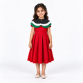 Girl wearing the Emirati Pride red pleated dress and removable black, white and green cape, front view on a white studio background.